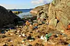 Steinete kystbukt full av plast og annet søppel mellom svabergene
