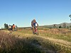Terrengsyklister på sti gjennom åpent fjellandskap i lav kveldssol