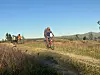 Terrengsyklister på sti gjennom åpent fjellandskap i lav kveldssol
