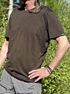 Person i brun T-skjorte og grå shorts står foran grønn buskvegetasjon.