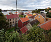 Utsikt over røde tak og hus på Innlandet i Kristiansund med havn og skyet himmel i bakgrunnen.